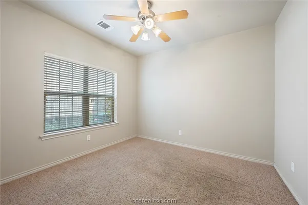 an empty room with windows and fan