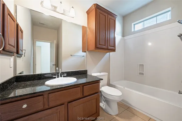 a bathroom with a granite countertop sink toilet a mirror and bathtub