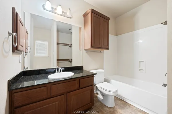 a bathroom with a granite countertop sink toilet a mirror and bathtub