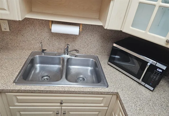 a bathroom with a granite countertop sink and white cabinets