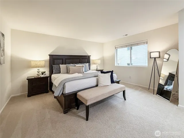 a spacious bedroom with a bed and a flat tv screen on a dresser