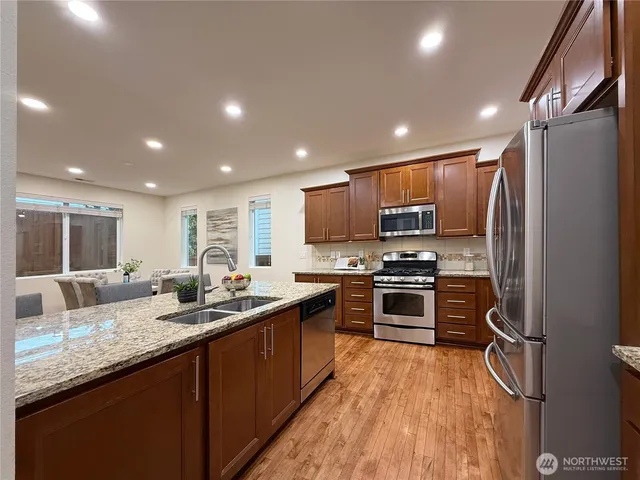 a dining room with stainless steel appliances kitchen island granite countertop a dining table chairs and a refrigerator
