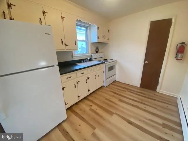 a kitchen with granite countertop white cabinets and white appliances