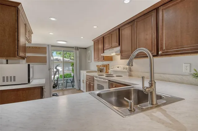 a kitchen with stainless steel appliances granite countertop a sink a stove and a refrigerator with wooden floor