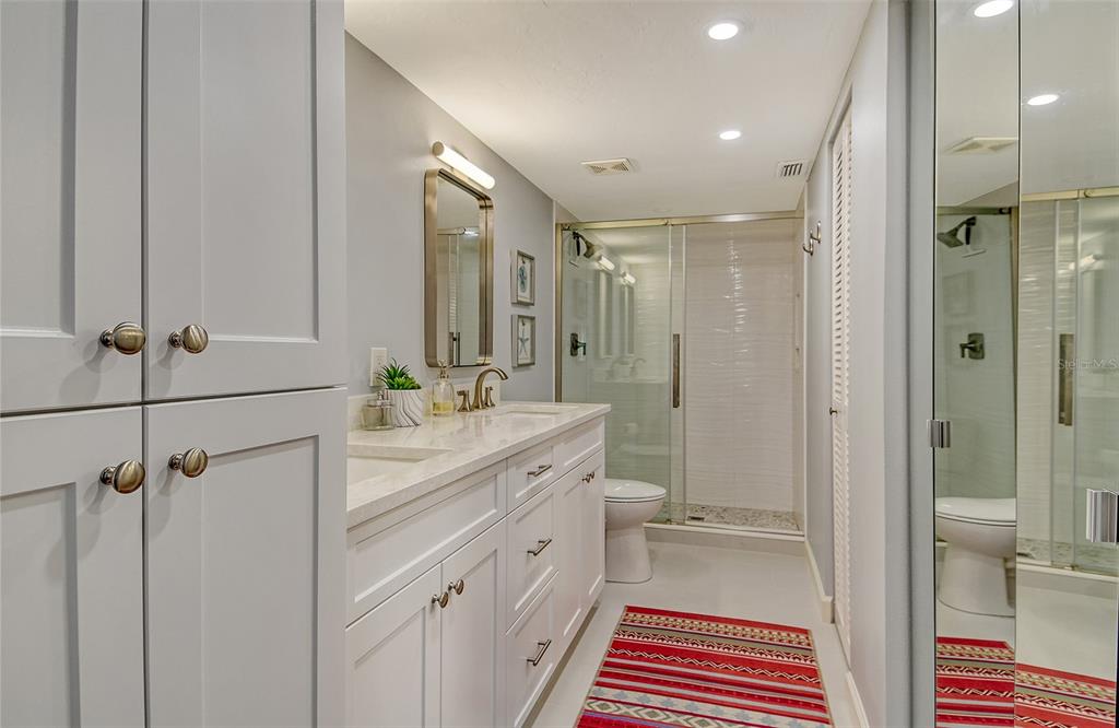 5246 Marsh Field Lane, Unit 1 Sarasota, FL 34235 - Photo 19 of 49 a bathroom with a double vanity sink a toilet a mirror and shower
