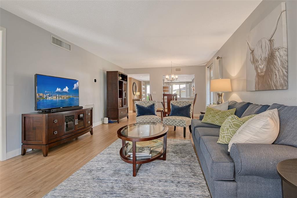 5246 Marsh Field Lane, Unit 1 Sarasota, FL 34235 - Photo 3 of 49 a living room with furniture a flat screen tv and paintings on the wall