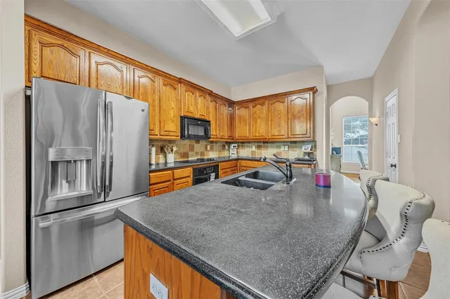 a kitchen with stainless steel appliances granite countertop a refrigerator a stove a sink a dining table and chairs