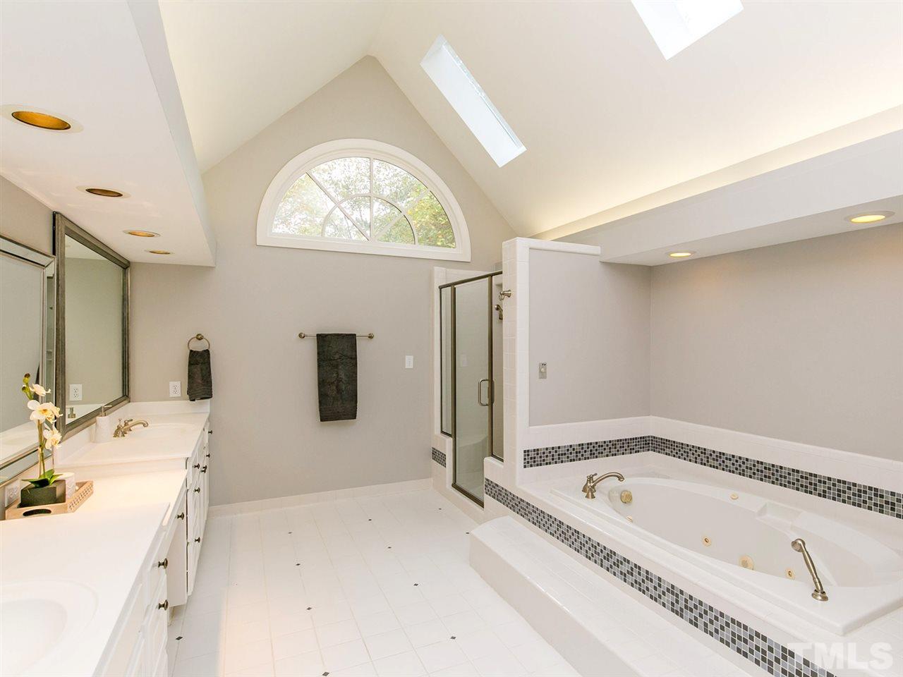 4038 John S Raboteau Wynd Raleigh, NC 27612 - Photo 17 of 25 a bathroom with a tub a double vanity sink and mirror