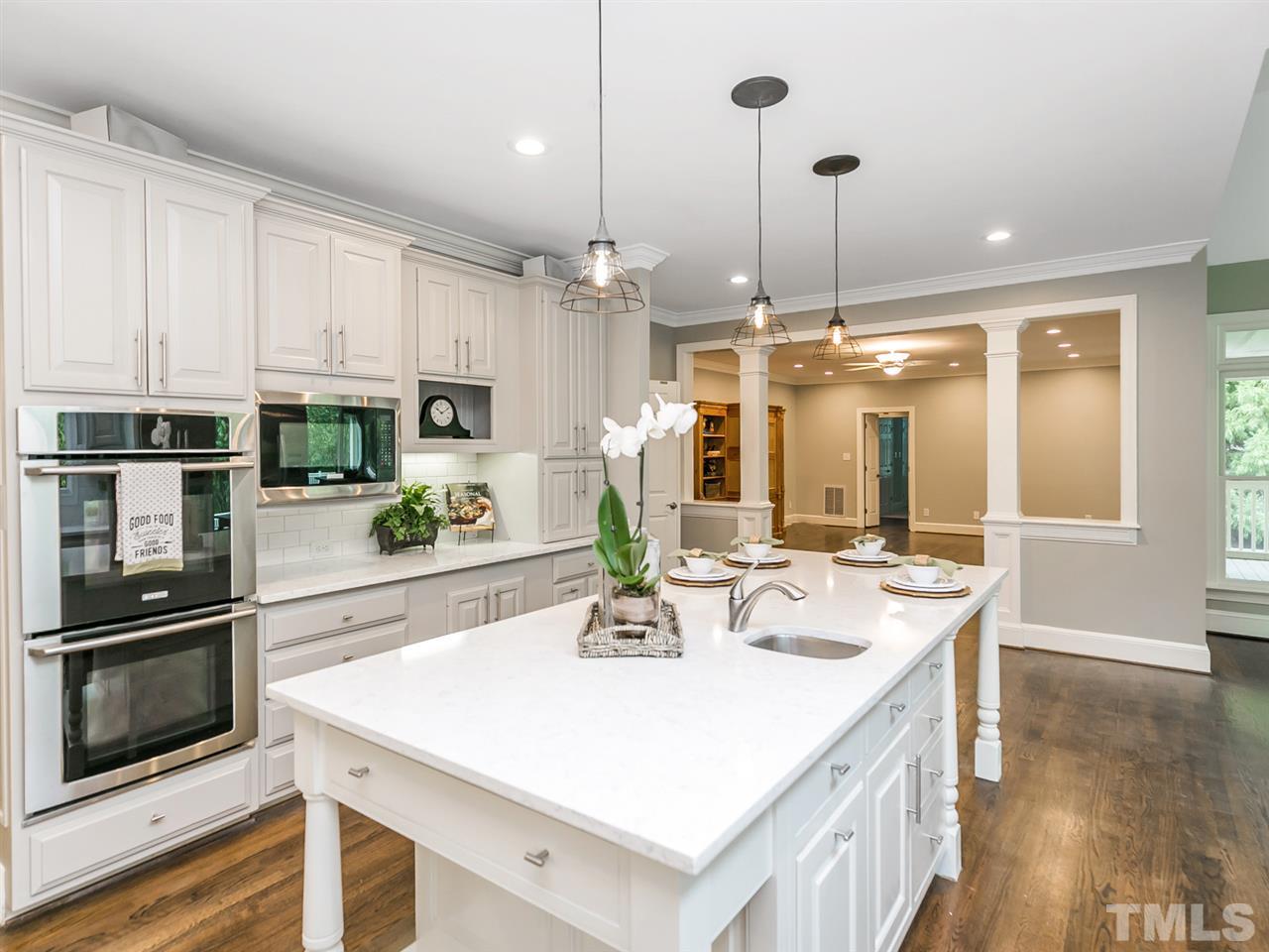 4038 John S Raboteau Wynd Raleigh, NC 27612 - Photo 6 of 25 a kitchen with stainless steel appliances kitchen island granite countertop a sink a stove and a refrigerator with wooden floor