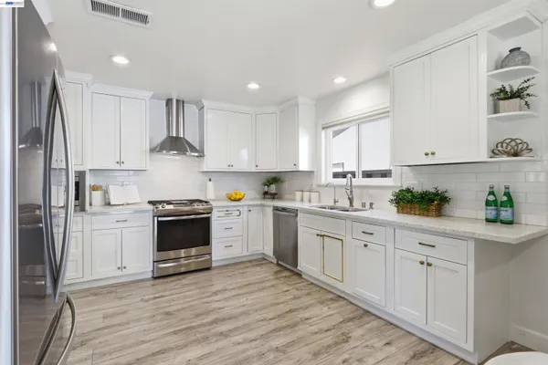 a kitchen with granite countertop white cabinets and stainless steel appliances