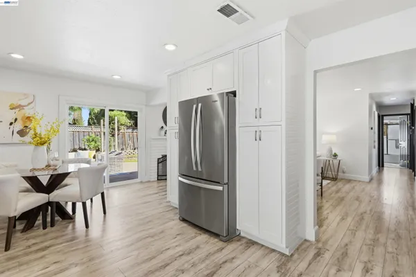 a kitchen with stainless steel appliances a refrigerator a stove a dining table and chairs with wooden floor