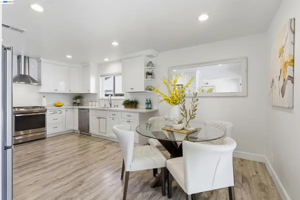 a kitchen with a dining table chairs stainless steel appliances and cabinets