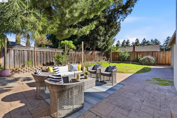 a view of a patio with couches chairs and a fire pit with wooden fence