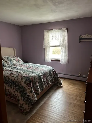 a bedroom with a bed wooden floor and window