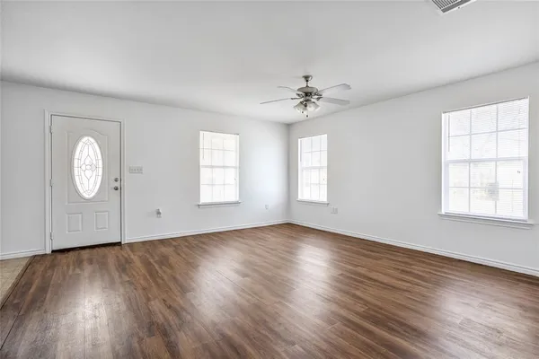 an empty room with wooden floor and windows