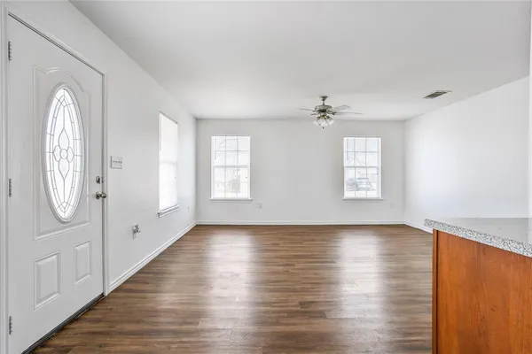 an empty room with wooden floor cabinet and windows