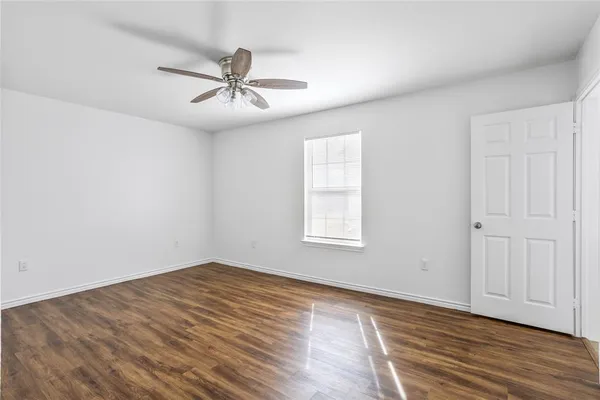 an empty room with wooden floor fan and windows