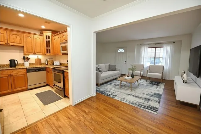 a living room with stainless steel appliances furniture a rug and a kitchen view