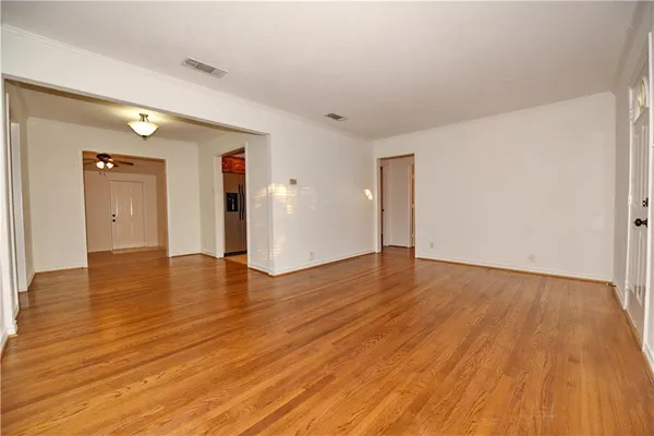 a view of an empty room with wooden floor and closet
