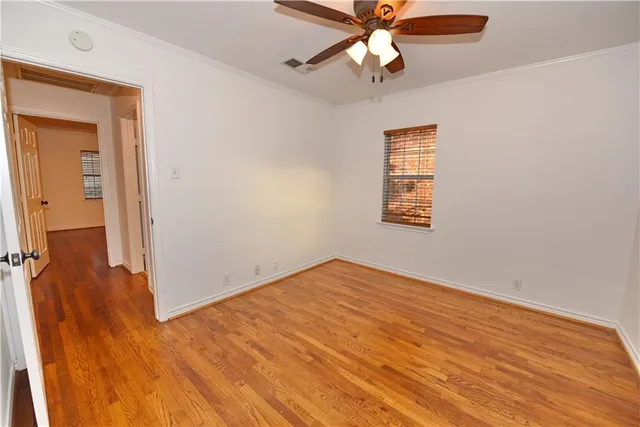 an empty room with wooden floor closet and fan