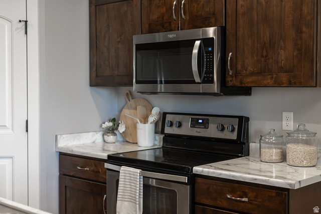 2483 South 1296th Street West Logan, UT 84321 - Photo 24 of 45 Kitchen featuring dark wood cabinetry, white marble-look countertops, and stainless steel appliances including an over-the-range microwave and electric range