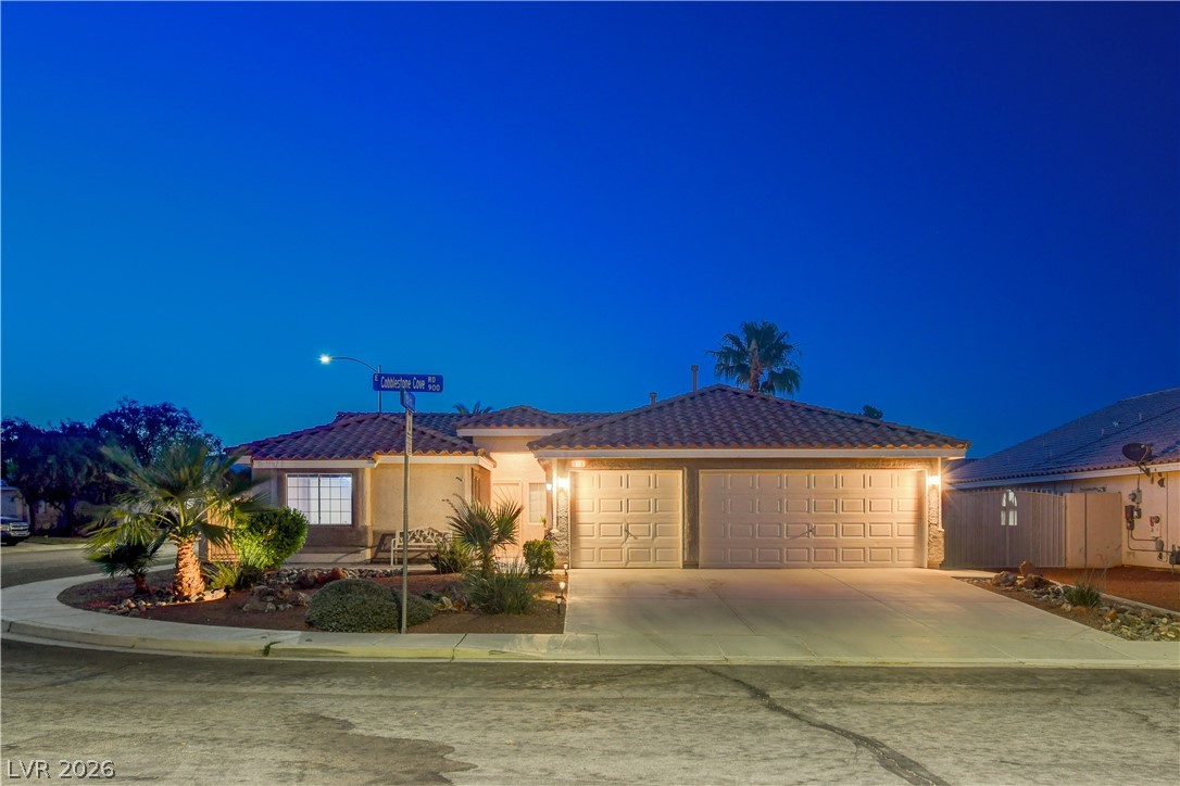 Illuminated at dusk, this inviting residence features a two-car garage and manicured front landscaping.