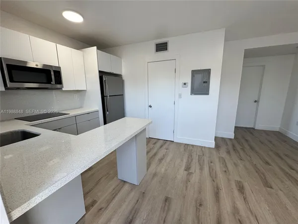 a kitchen with stainless steel appliances a microwave and wooden floor