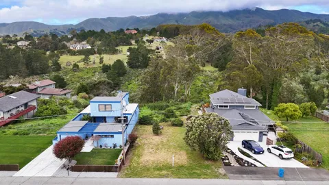 an aerial view of residential houses with outdoor space and a street view