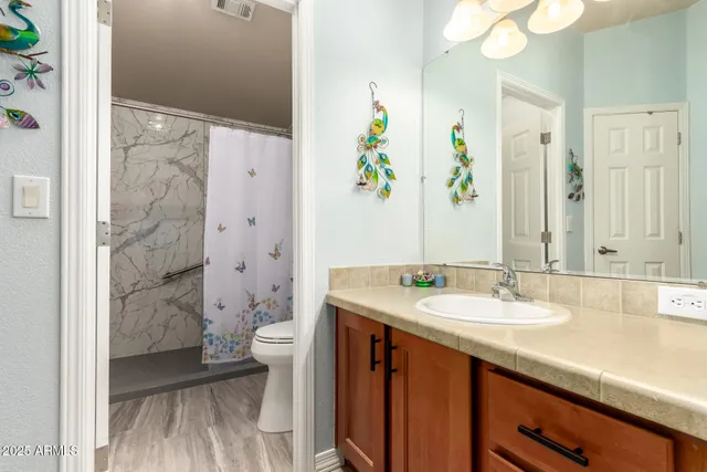 a spacious bathroom with a granite countertop sink a toilet a large mirror and shower