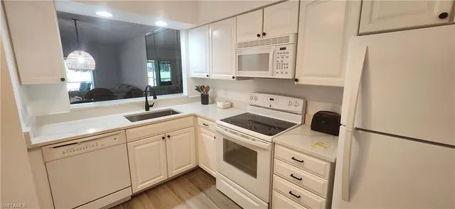 a kitchen with white cabinets and white appliances