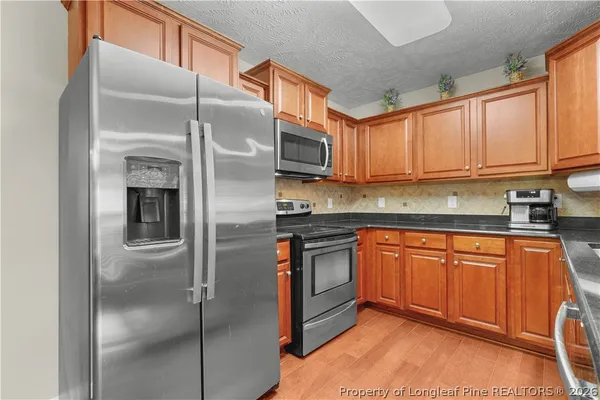 a kitchen with stainless steel appliances granite countertop a refrigerator a stove and a sink with cabinets