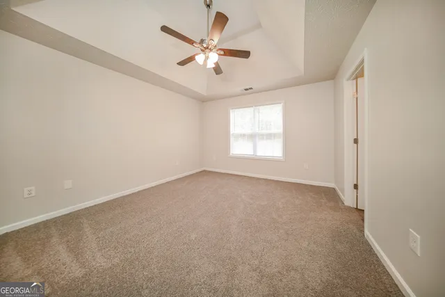 an empty room with windows and fan