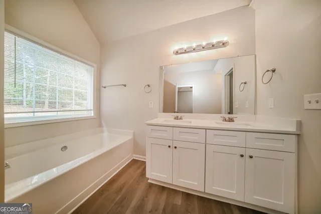 a spacious bathroom with a double vanity sink a mirror and a bathtub