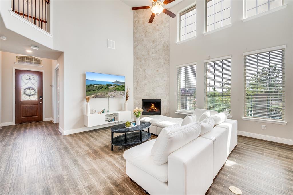 6117 Hall Road Frisco, TX 75034 - Photo 4 of 32 Living area with wood finished floors, a ceiling fan, a high ceiling, and a large fireplace