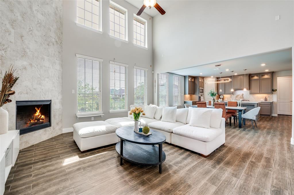6117 Hall Road Frisco, TX 75034 - Photo 6 of 32 Living area featuring a large fireplace, a ceiling fan, wood finish floors, and a high ceiling