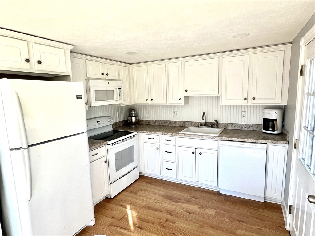 495 Sandwich Road Falmouth, MA 02536 - Photo 2 of 9 a kitchen with white cabinets and white appliances