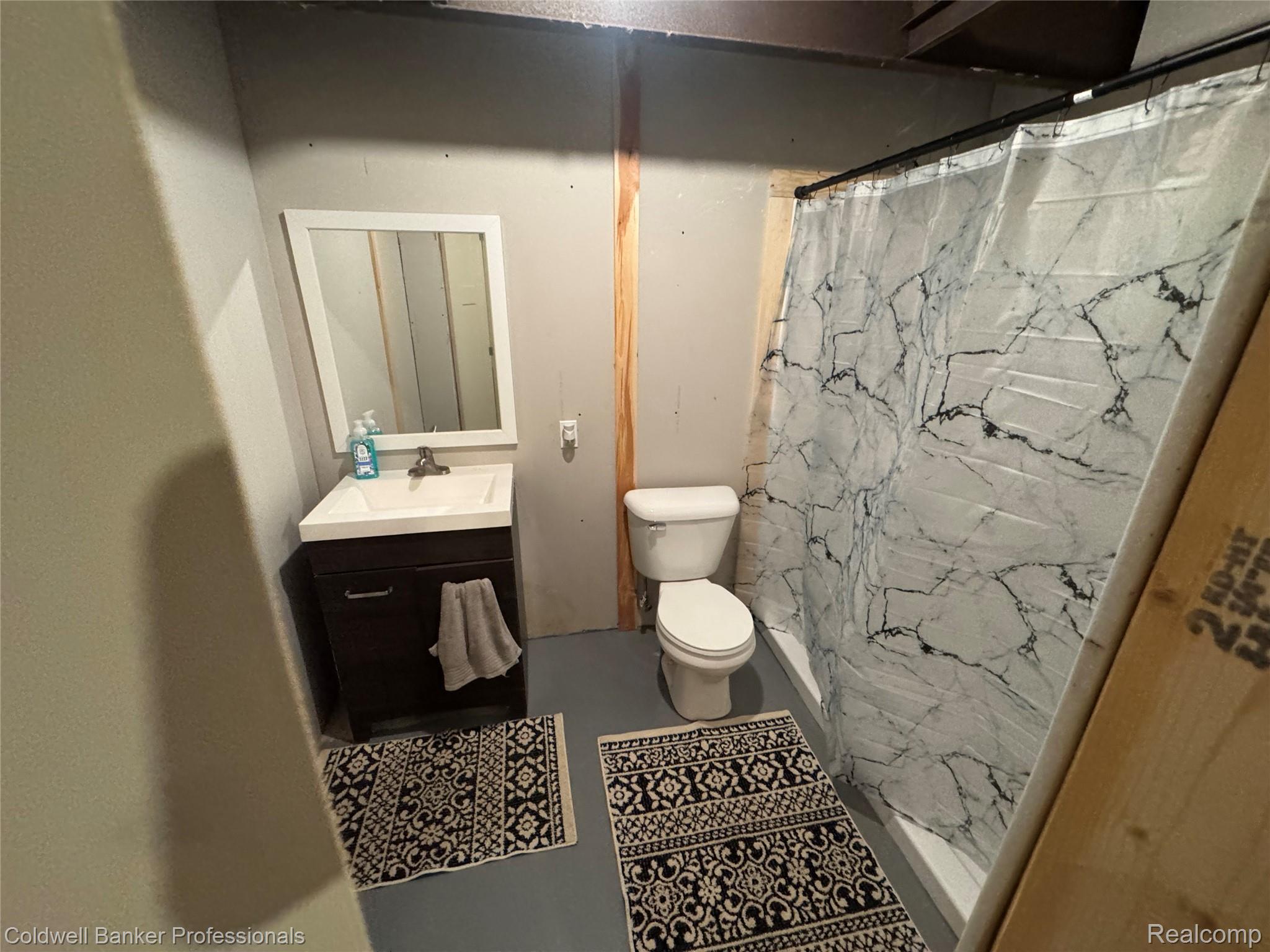 5323 English Road Clifford, MI 48727 - Photo 46 of 46 Vanity with white square sink basin, wall-mounted mirror, and shower with patterned curtain