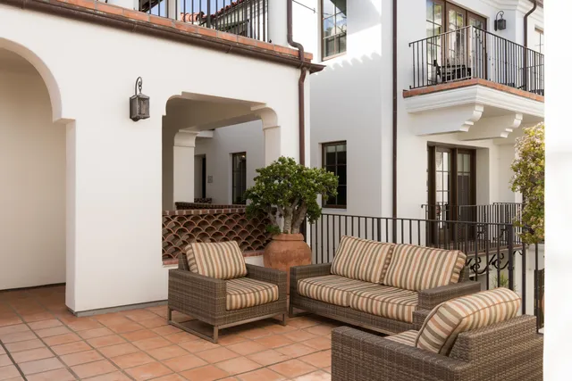 a living room with stainless steel appliances furniture a rug and a kitchen view