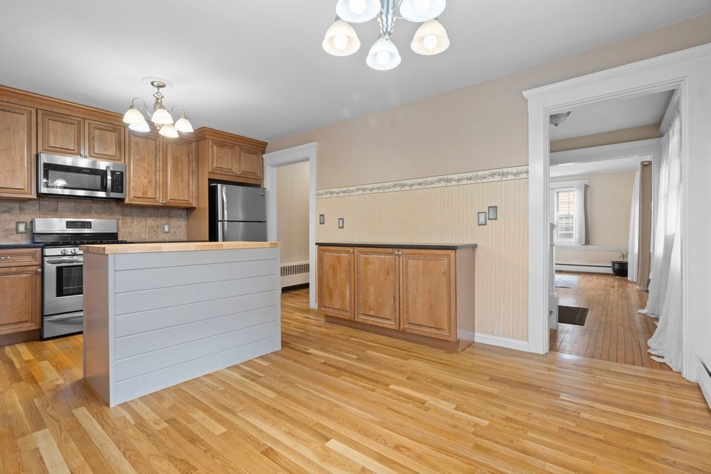 33 Nowell Road Melrose, MA 02176 - Photo 8 of 35 a kitchen with kitchen island granite countertop a stove top oven a sink and cabinets