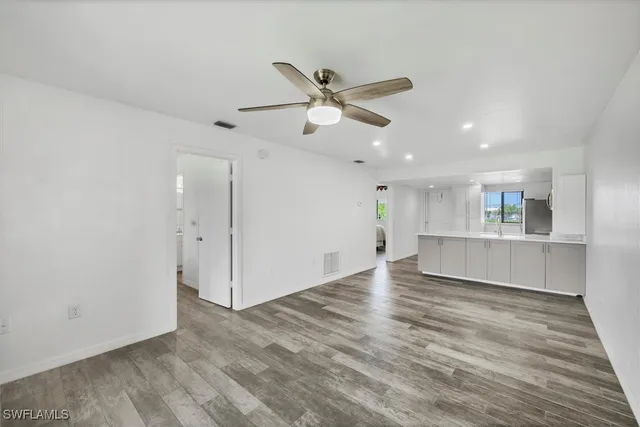 a view of kitchen and empty room with wooden floor