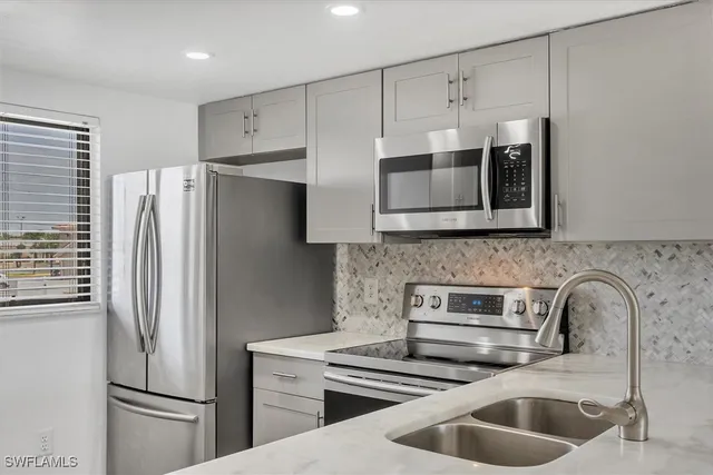 a kitchen with stainless steel appliances a refrigerator a sink a stove and cabinets