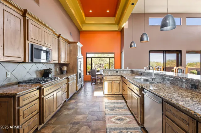 a large kitchen with stainless steel appliances granite countertop a lot of counter space and a sink