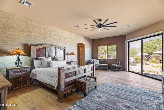 a bedroom with a large bed and a large window with wooden floor