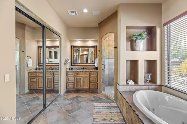 a bathroom with a granite countertop tub shower and mirror