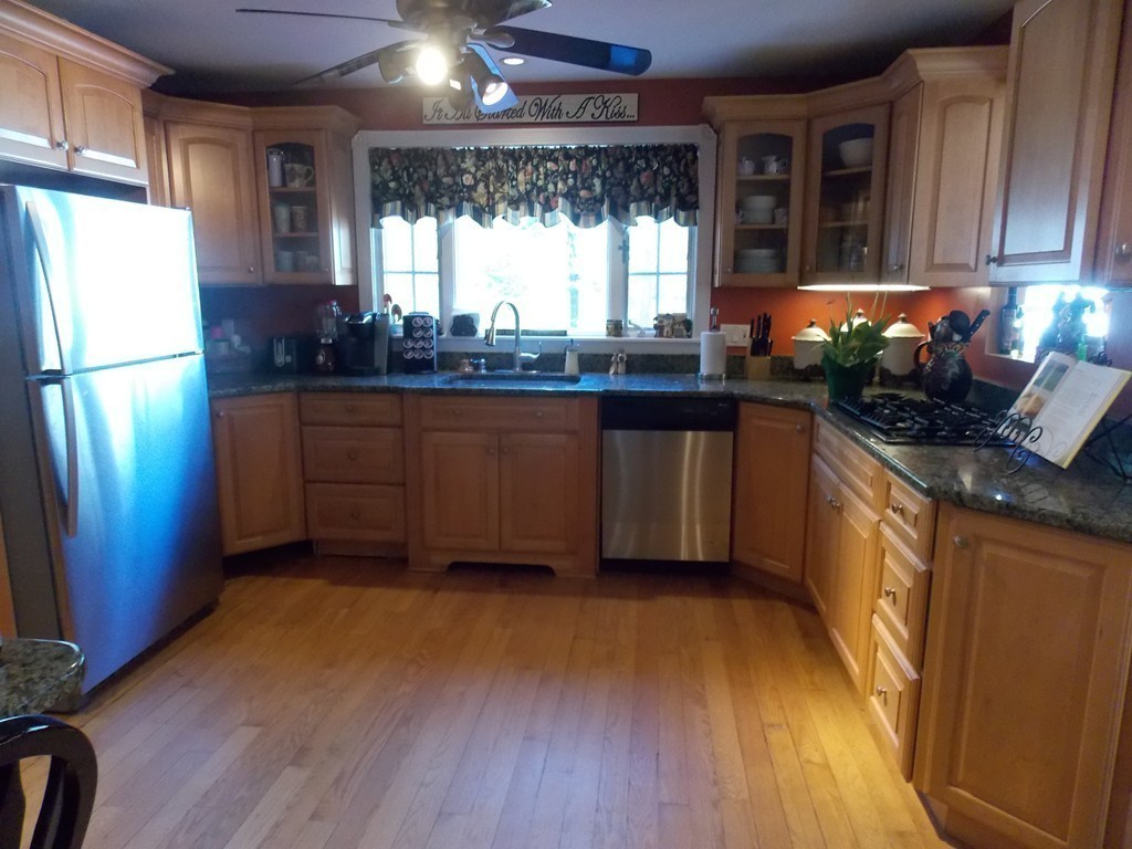 79 Haverhill Road Amesbury, MA 01913 - Photo 6 of 25 a kitchen with stainless steel appliances granite countertop a refrigerator a sink dishwasher a stove a dining table and chairs with wooden floor
