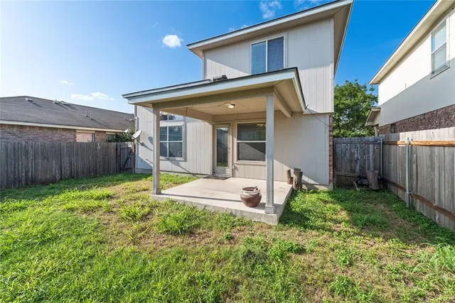 a view of a house with backyard and wooden fence