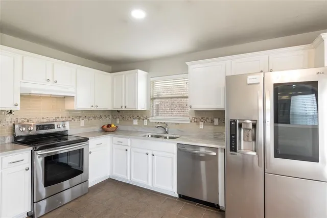 a kitchen with white cabinets and white appliances