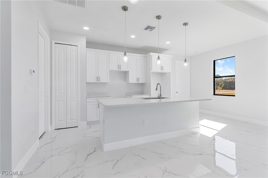 1152 Randolph Street Lehigh Acres, FL 33974 - Photo 6 of 50 a large white kitchen with kitchen island a sink a stove a refrigerator and white cabinets