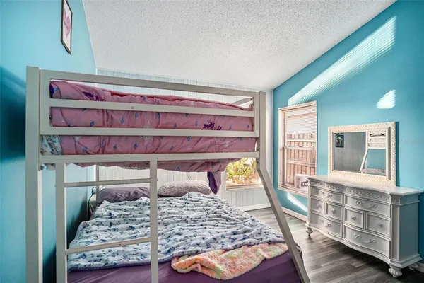 a bedroom with a bed a dresser and large window