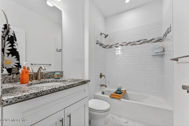 a bathroom with a granite countertop sink a toilet and shower